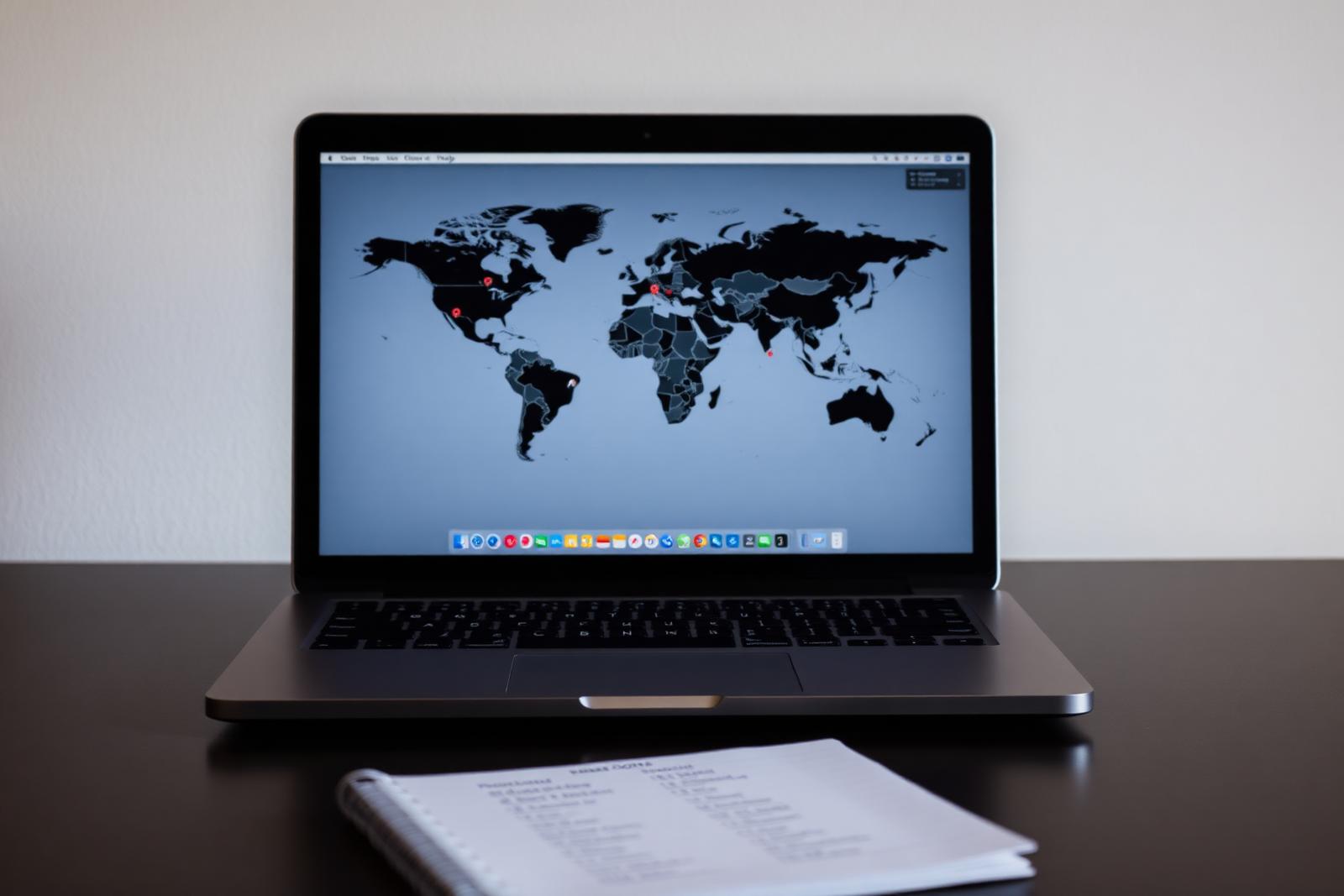 Laptop on a desk displaying a world map with country markers, a notebook of language and country codes beside it — international SEO planning.